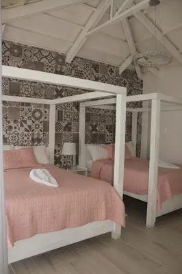 a bedroom with two beds with pink sheets at Hotel Arenal Vista Lodge in Fortuna