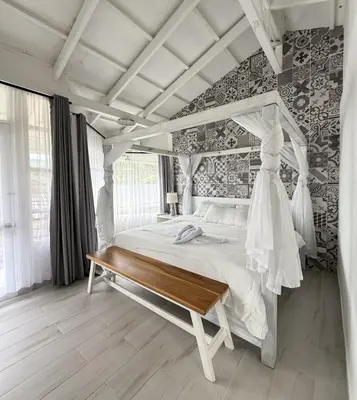 a bedroom with a white bed and a wooden bench at Hotel Arenal Vista Lodge in Fortuna
