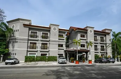 a large white building with cars parked in front of it at Macaws Ocean Club Apartamento # 18 in Jacó