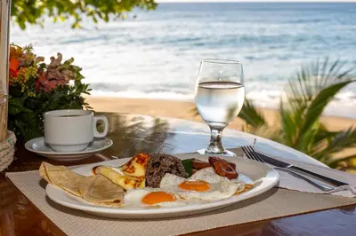 a plate of breakfast food and a glass of water at Tango Mar Beachfront Boutique Hotel & Villas in Tambor