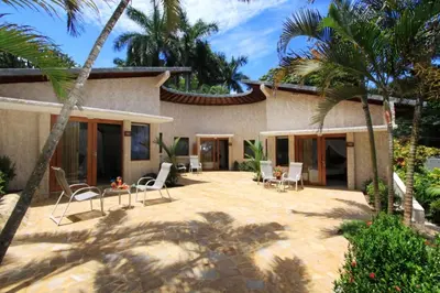 a house with a patio with chairs and palm trees at Tango Mar Beachfront Boutique Hotel & Villas in Tambor