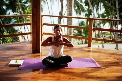 a woman sitting on a yoga mat on a wooden floor at Tango Mar Beachfront Boutique Hotel & Villas in Tambor