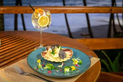 a plate of food and a glass of wine on a table at Tango Mar Beachfront Boutique Hotel & Villas in Tambor