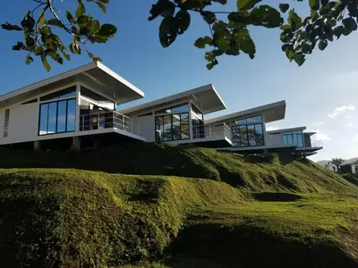 a house on top of a grassy hill at Hotel Laguna Arenal in Unión