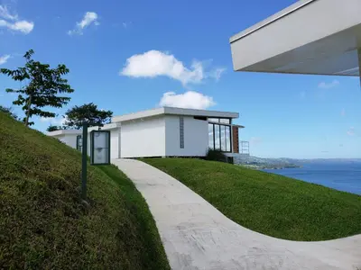 a white building on top of a grassy hill at Hotel Laguna Arenal in Unión