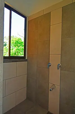 a bathroom with a shower with a window at Aves de Tierras Altas in Bijagua