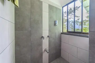 a shower stall in a bathroom with a window at Aves de Tierras Altas in Bijagua