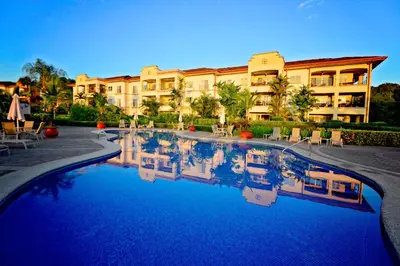 a hotel with a swimming pool in front of a building at HRG Condos at Los Sueños in Jacó