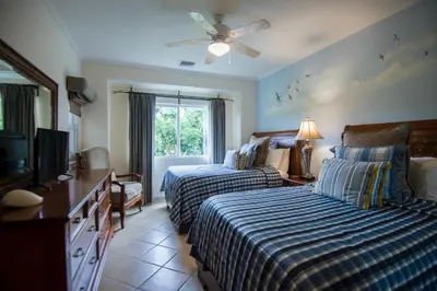 a bedroom with two beds and a flat screen tv at HRG Condos at Los Sueños in Jacó