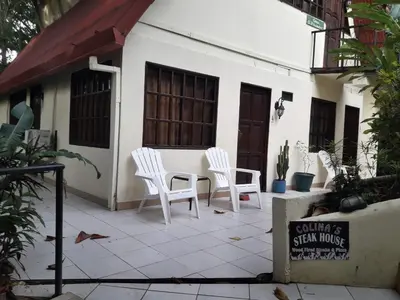 a group of white chairs sitting outside of a building at Hotel La Colina in Manuel Antonio
