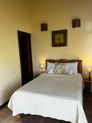 a bedroom with a bed with white sheets and pillows at Hotel La Colina in Manuel Antonio