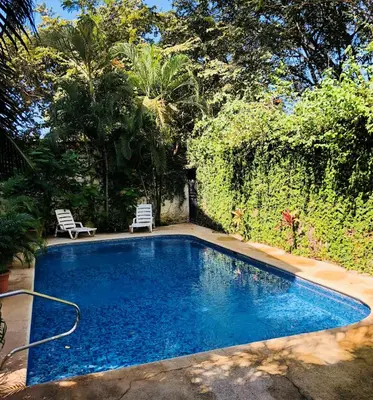a swimming pool in a yard with two chairs at La Buena Vida 2 in Tamarindo