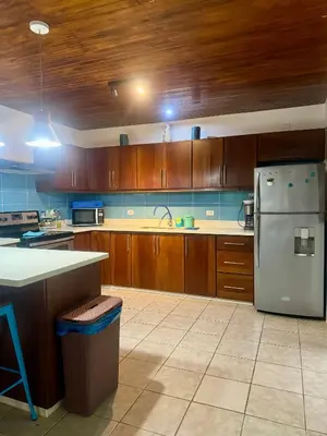 a kitchen with wooden cabinets and a white refrigerator at La Buena Vida 2 in Tamarindo