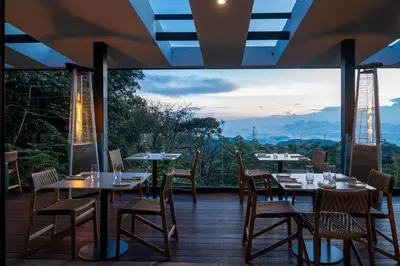 a restaurant with tables and chairs on a deck at Koora Monteverde a Cloud Forest Hotel by Sandglass in Monteverde Costa Rica