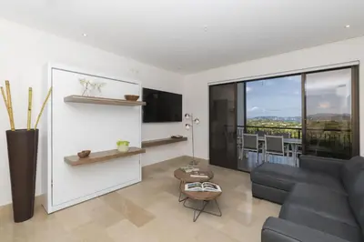 a living room with a couch and a large window at Modern 2BR Condo Partial Ocean View - Roble Sabana - Reserva Conchal Golf Resort in Playa Conchal