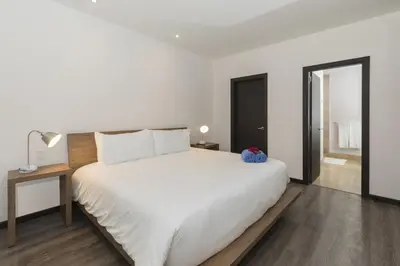 a white bedroom with a large bed and a table at Modern 2BR Condo Partial Ocean View - Roble Sabana - Reserva Conchal Golf Resort in Playa Conchal