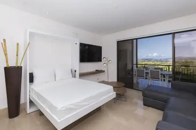 a white bedroom with a white bed and a couch at Modern 2BR Condo Partial Ocean View - Roble Sabana - Reserva Conchal Golf Resort in Playa Conchal