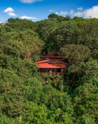 a house in the middle of a hill with trees at El Sol Monteverde in Monteverde Costa Rica