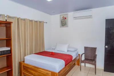 a small bedroom with a bed and a chair at Hotel Vive Uvita in Uvita