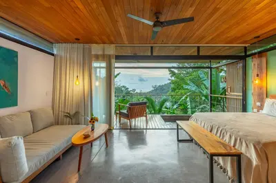 a bedroom with a bed and a couch and a table at The Green House, Santa Teresa - Adults Only in Santa Teresa Beach