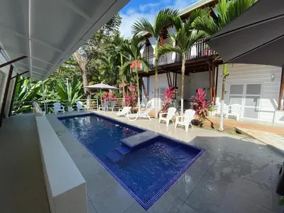 a swimming pool with chairs and a house at Ballena Dorada Lodge in Uvita