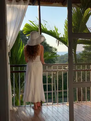 a girl in a white dress and a hat on a balcony at Ballena Dorada Lodge in Uvita