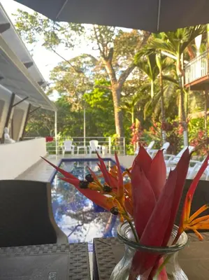a vase of flowers sitting on a table next to a pool at Ballena Dorada Lodge in Uvita