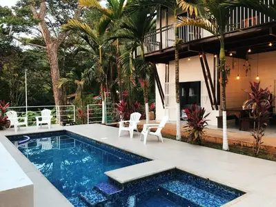a swimming pool with chairs and a house at Ballena Dorada Lodge in Uvita