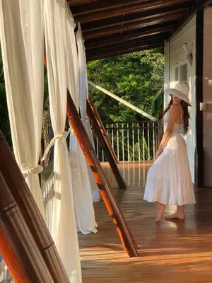 a woman in a white dress walking on a porch at Ballena Dorada Lodge in Uvita