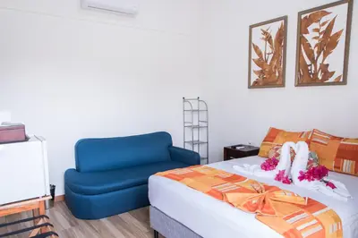 a bedroom with a bed and a blue chair at Hotel Eco Arenal in Fortuna