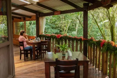 a woman sitting at a table on a porch at Cabañas el Bosque in Turrialba