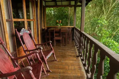a porch with two rocking chairs and a table at Cabañas el Bosque in Turrialba