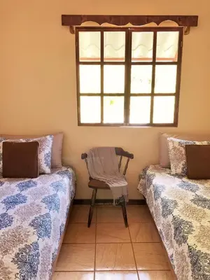 a chair sitting between two beds in a room with a window at Cabaña Vista Verde in Cartago