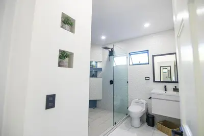 a bathroom with a toilet and a glass shower at Apartamentos Cristal in Quepos