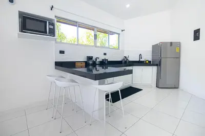 a white kitchen with a counter and a refrigerator at Apartamentos Cristal in Quepos