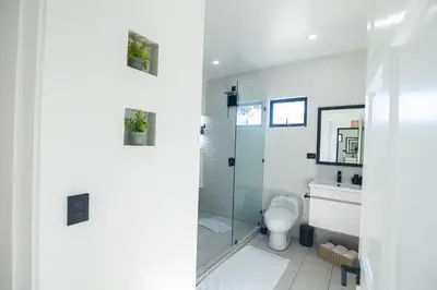 a bathroom with a toilet and a glass shower at Apartamentos Cristal in Quepos