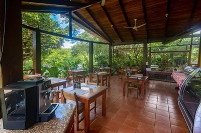 a restaurant with tables and chairs and a tv at Rinconcito Lodge in Liberia