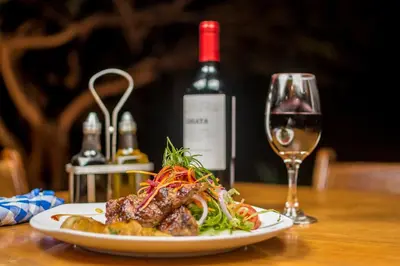 a plate of food on a table with a glass of wine at Rinconcito Lodge in Liberia