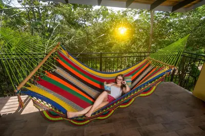 a woman sitting in a hammock while talking on a cell phone at Rinconcito Lodge in Liberia