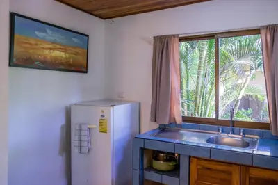 a kitchen with a refrigerator and a sink and a window at Zula Inn Aparthotel in Santa Teresa Beach