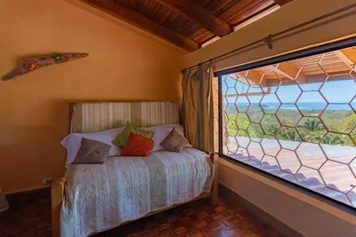 a bedroom with a bed and a large window at Villa Mango B&B in Nosara