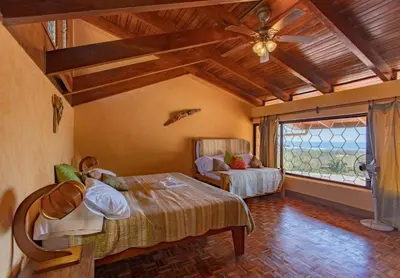 a bedroom with a bed and a window and a couch at Villa Mango B&B in Nosara