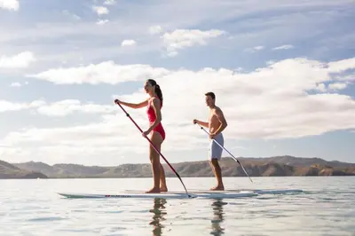 a man and woman on a paddle board on the water at Four Seasons Resort Peninsula Papagayo, Costa Rica in Papagayo, Guanacaste