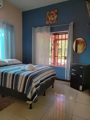 a bedroom with a bed and a window and a mirror at Hotel Campestre Arenal in Fortuna