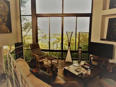 a man laying on a couch in a living room with a large window at Salamandra Room in Escazu