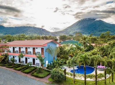 a house with a pool and mountains in the background at Hotel Vista del Cerro in Fortuna