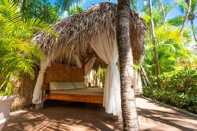 a bed in a straw hut with a palm tree at Jardin del Eden Boutique Hotel in Tamarindo