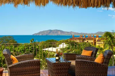 a patio with chairs and a table with a view of the ocean at Jardin del Eden Boutique Hotel in Tamarindo