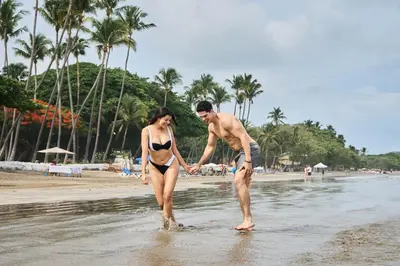 a man and a woman walking in the water on the beach at Jardin del Eden Boutique Hotel in Tamarindo