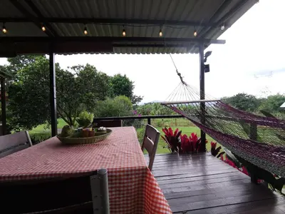 a table and hammock on a porch with a table and a hammock at Dreamcatcher house in Sarchí